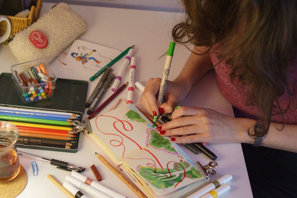 Colorful artistic workspace depicting a person drawing with markers and pencils.